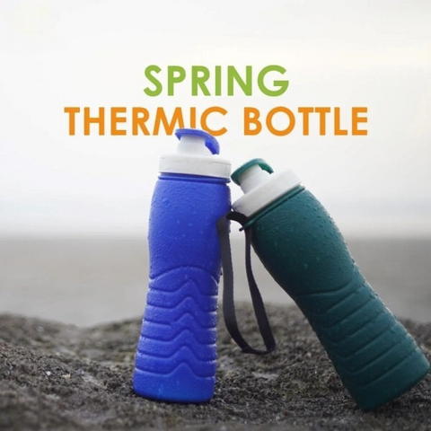 two thermic bottles, one in blue and the other in green, woth textured bodies and white caps. The bottles are placed on a sandy surface with text "Spring Thermic Bottle" displayed above them.