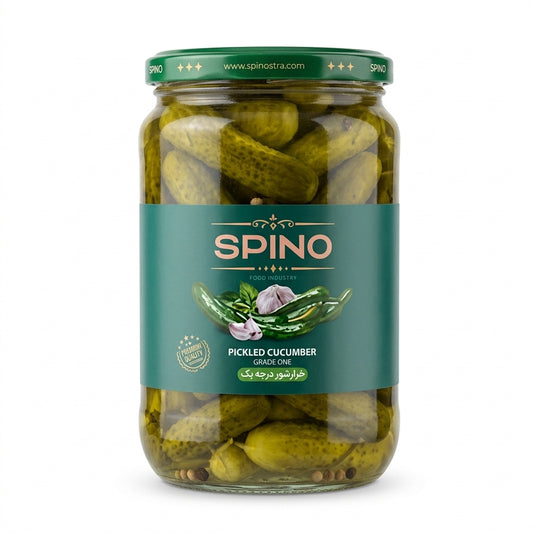 A glass jar of Spino Pickled Cucumber Garlic Oil, featuring green pickled cucumbers inside, a dark green lid, and a dark teal label with the brand name 'SPINO' in gold.