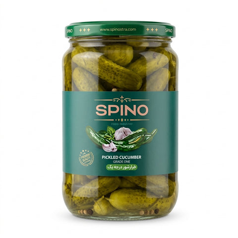 A glass jar of Spino Pickled Cucumber Garlic Oil, featuring green pickled cucumbers inside, a dark green lid, and a dark teal label with the brand name 'SPINO' in gold.